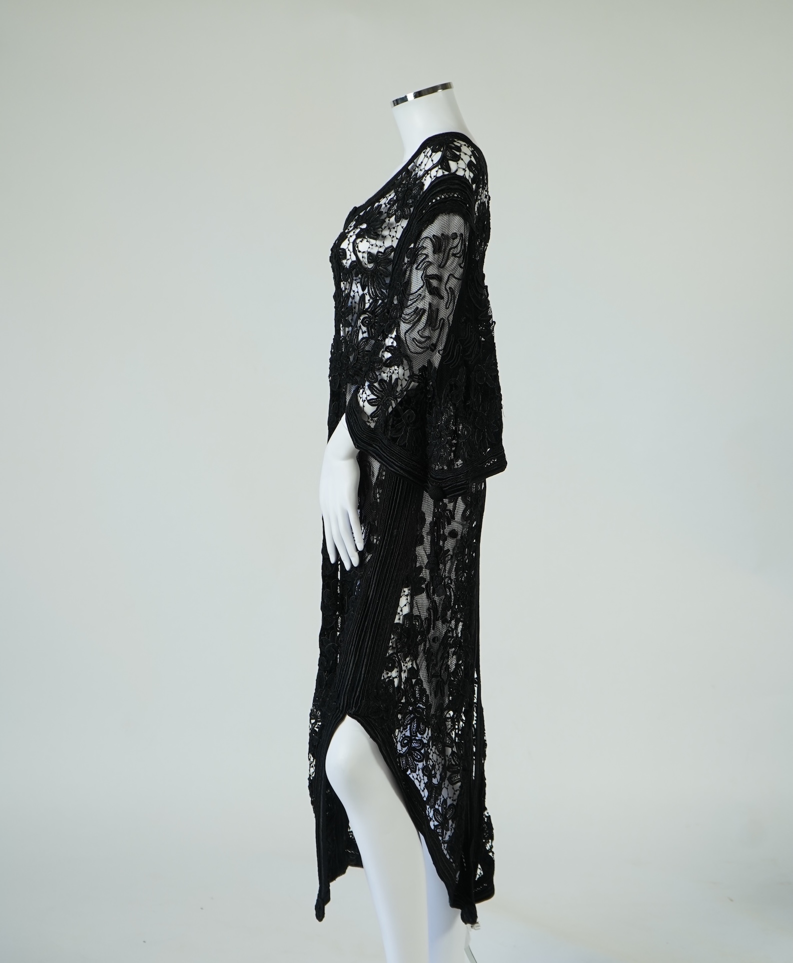 A late 19th century stylish ornate black silk tape lace evening coat/dress. Designed with a wide open neck, short bell sleeves with long tassels, four large buttons at the front and tails at the front and back. 130cm lon